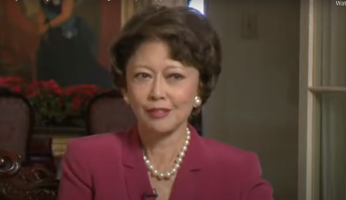Jean Hayashi Ariyoshi wearing a plum blazer and pearls discusses working in the pineapple fields